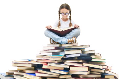 Foto van een meisje dat op een stapel boeken zit te lezen